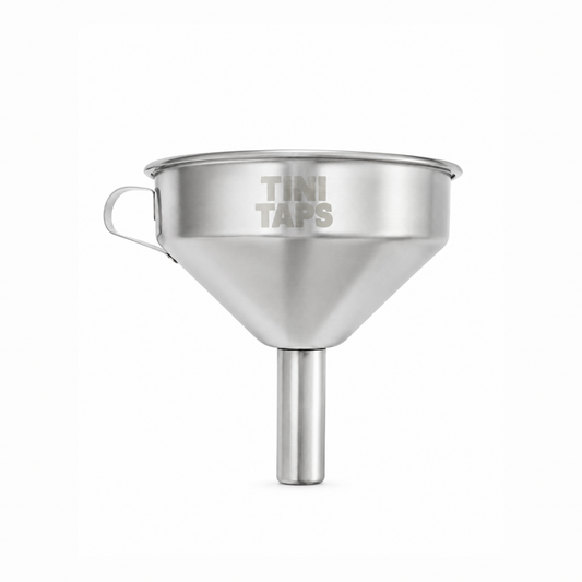 A stainless steel funnel with a side handle and a vertical spout, with engraved 'TINI TAPS' logo on a plain white background.