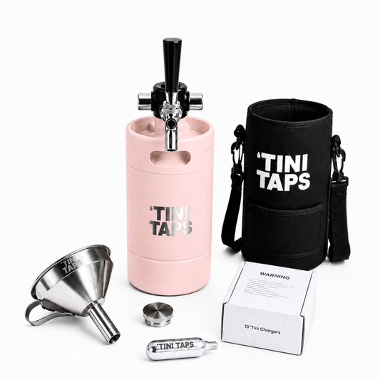 Tini Taps portable mini keg starter kit on a white background, including a light pink keg with tap handle, black cooler sleeve with white TINI TAPS text, stainless steel funnel, metal lid, CO2 cylinder, and white product box.